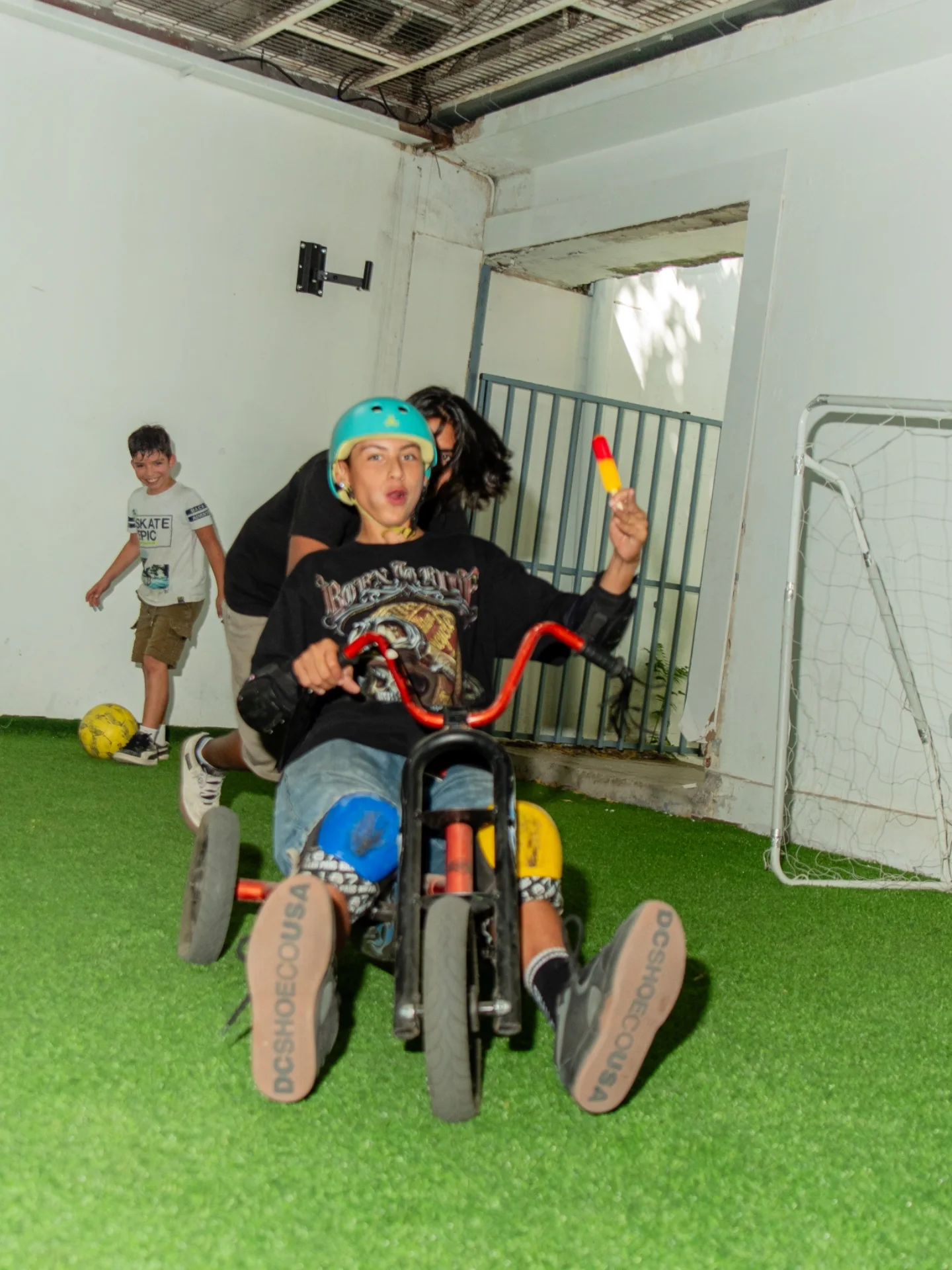 Niño con casco manejando un triciclo de carrera sobre el pasto sintético